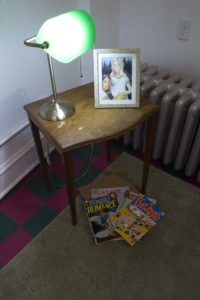 Photo Of Gallery, Installation Of Side Table With Photo, Banker's Lamp And Magazines On Green Rug